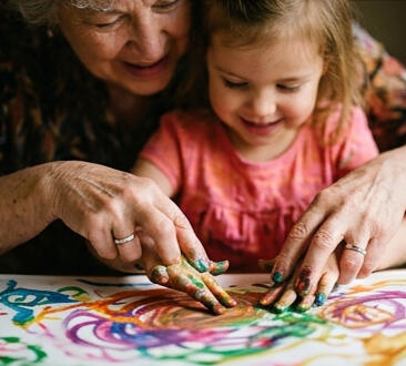 Family Legacy Documentary An image showing a grandmother painting with her granddaughter.
